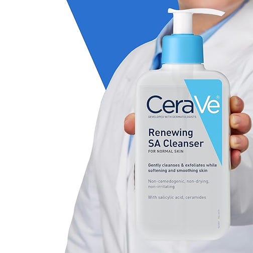 A person in a white coat holds a bottle of CeraVe Renewing SA Cleanser for normal skin.