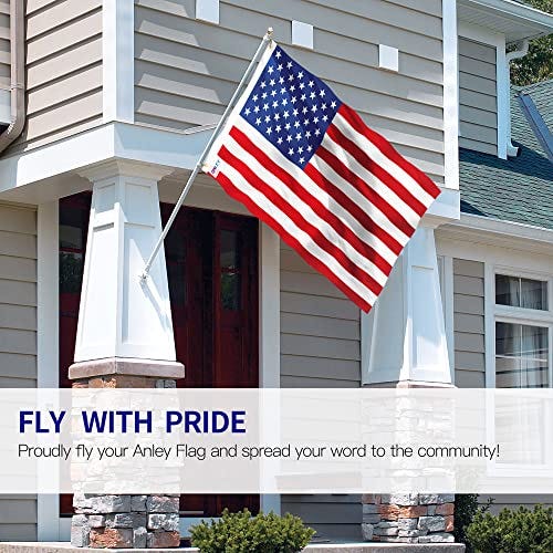 An American flag with 50 stars and 13 stripes is displayed outside a house, attached to a white flagpole.