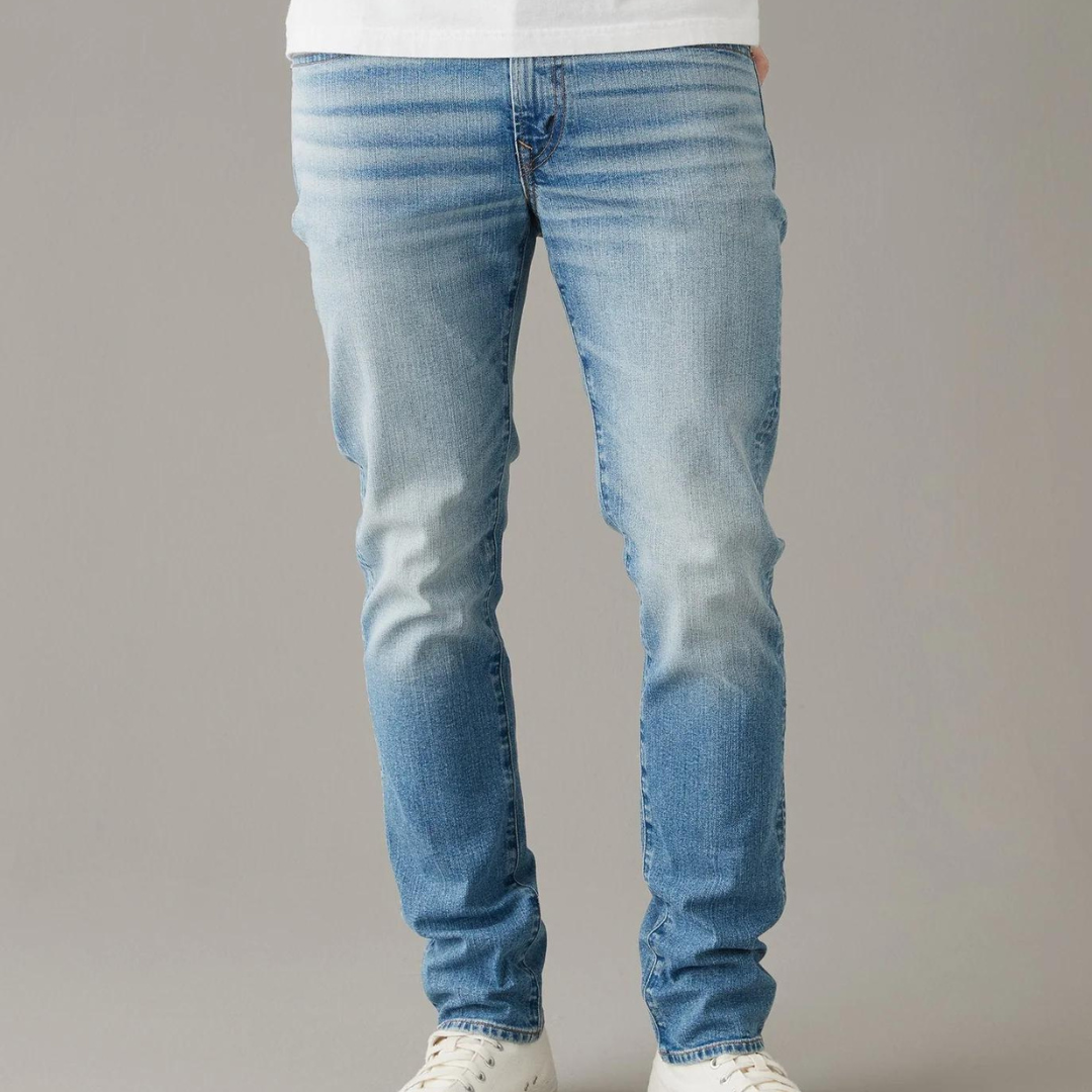 A person wearing light blue faded jeans and white sneakers.