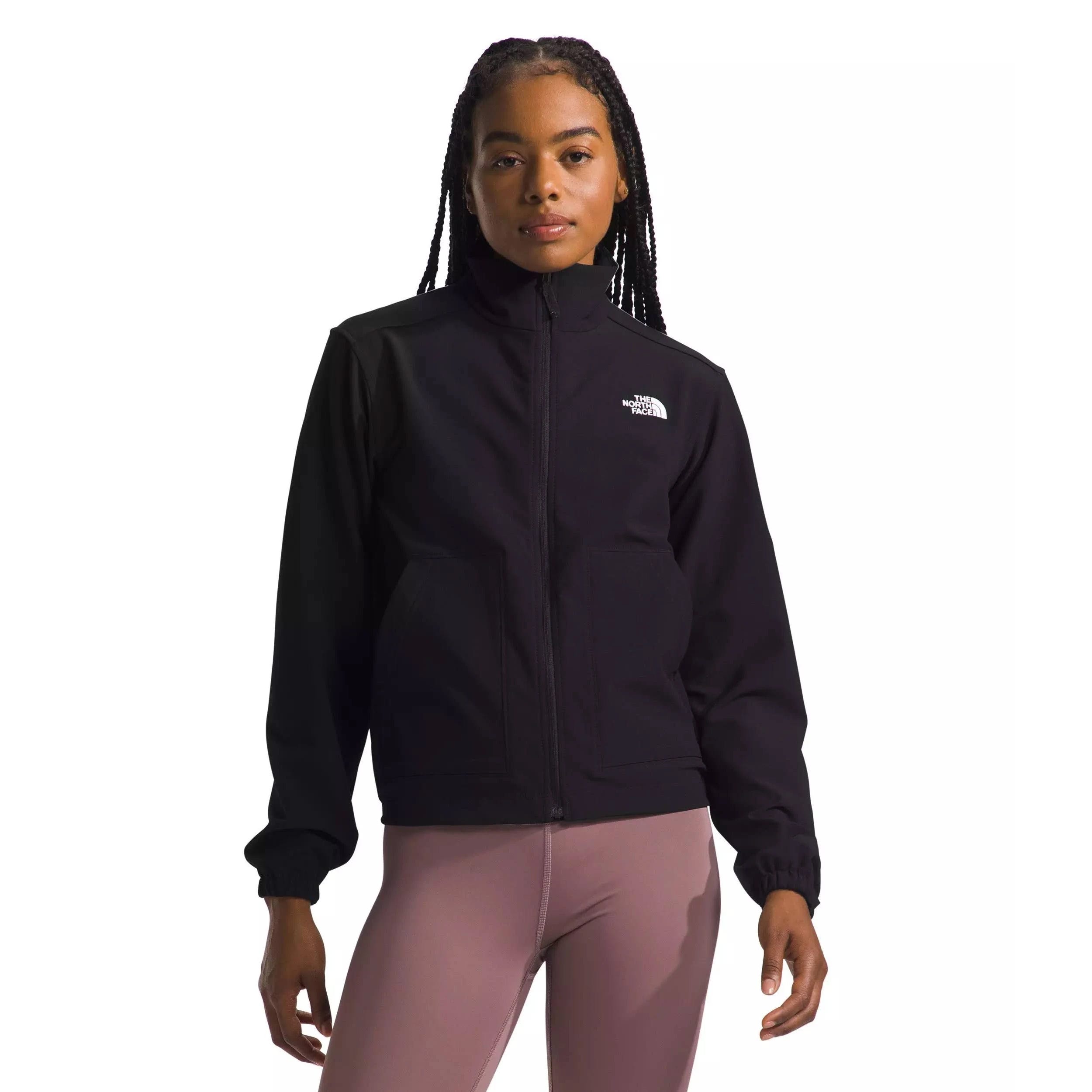 The North Face Stretch Jacket is black with a front zip closure, featuring two front pockets and an elastic cuff. The brand logo is displayed on the upper chest. It’s paired with high-waisted, light pink leggings.