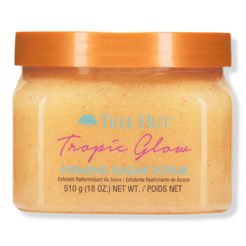 Tree Hut Tropic Glow Firming Sugar Scrub, 510g (18 oz.), features an exfoliating and firming formula with a tropical fragrance, packaged in a clear container with an orange lid.