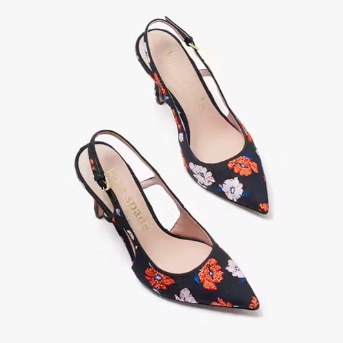 A pair of black slingback shoes with a pointed toe and floral pattern.