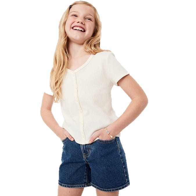 A girl wearing a short-sleeved, button-up white top paired with denim shorts.
