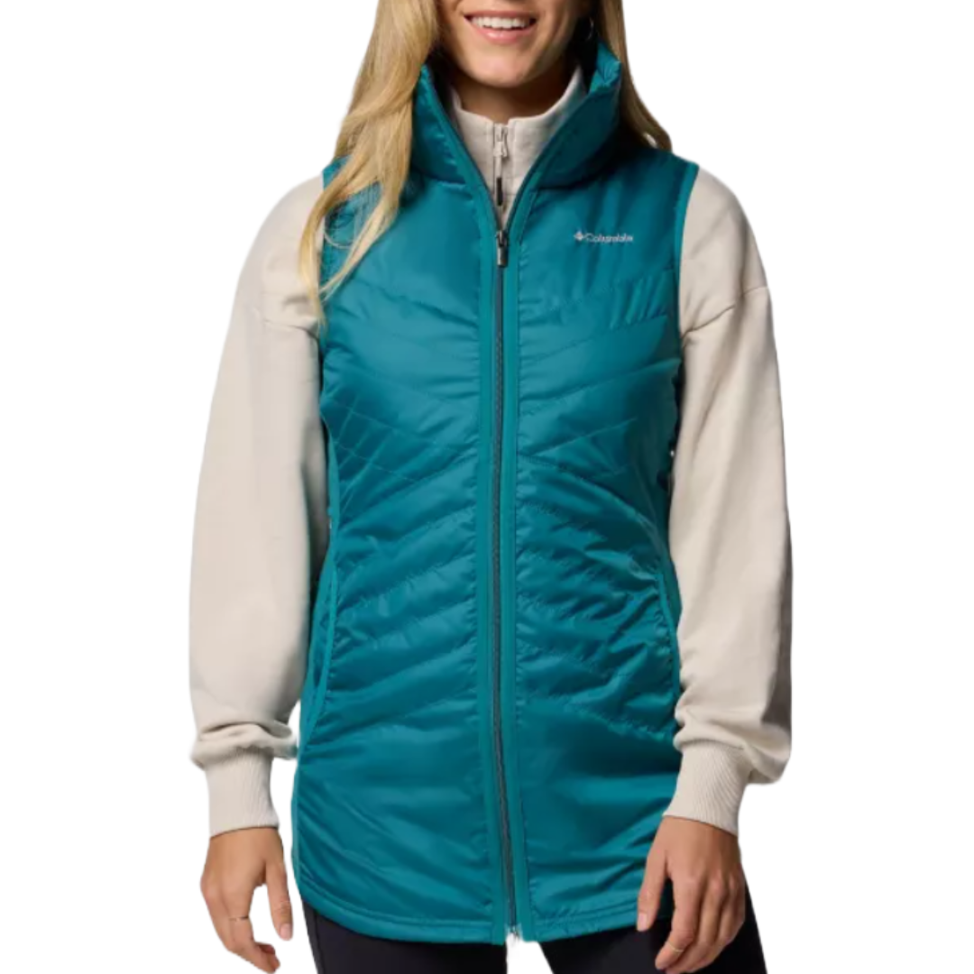 A woman wears a teal Columbia puffer vest over a light-colored long-sleeve shirt.