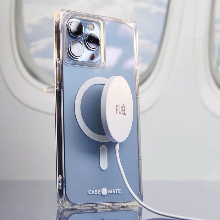 A clear smartphone case on an iPhone with a triple camera setup and a white, round magnetic wireless charger attached to its back.