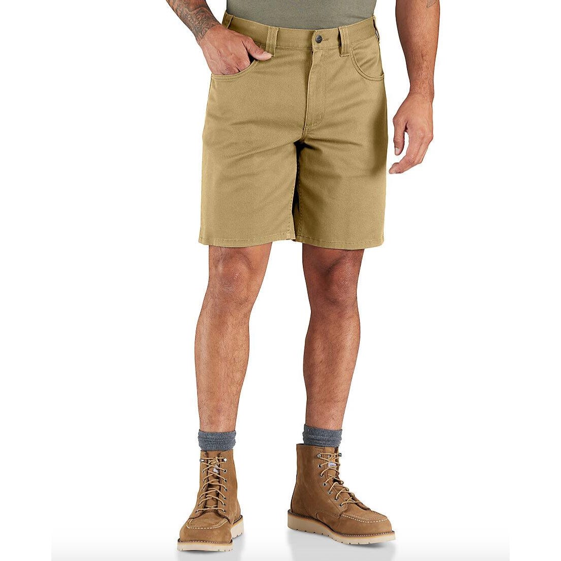 Carhartt Force Relaxed Shorts are tan, knee-length work shorts featuring a relaxed fit, with front and back pockets. They're styled with a button closure and shown paired with brown work boots and gray socks.