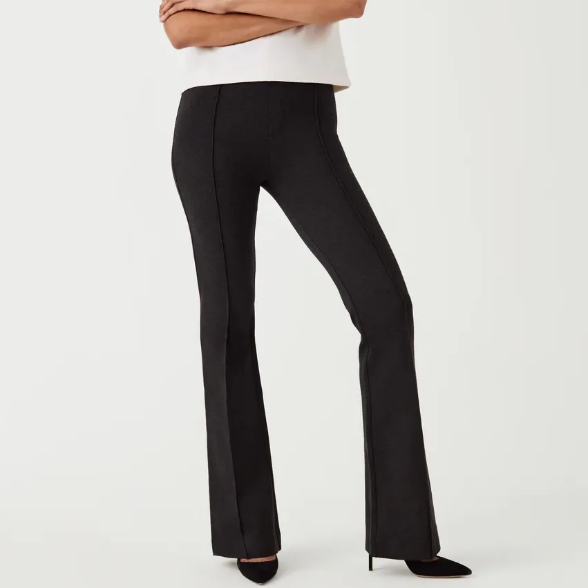 Black flared trousers with a mid-rise waist worn by a person standing with hands on hips.