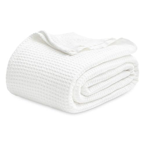 A folded white cotton blanket with a textured waffle weave pattern.