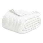 A folded white cotton blanket with a textured waffle weave pattern.