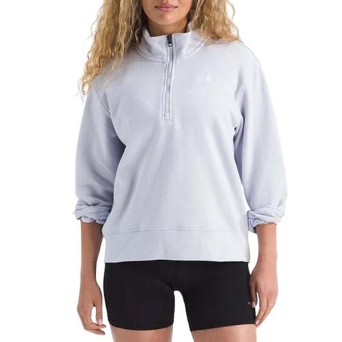 A person wearing a light-colored half-zip pullover and black shorts.