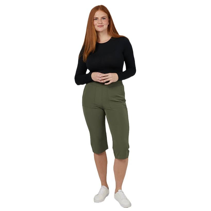 A person is wearing a black long-sleeve top, green knee-length shorts, and white sneakers.