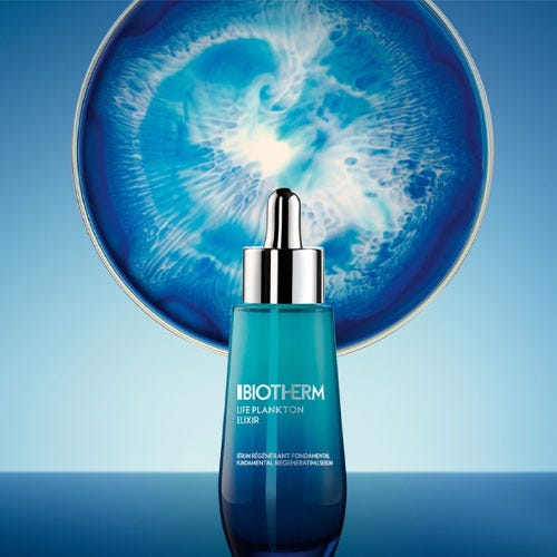 Biotherm Life Plankton Elixir serum in a blue bottle with a dropper, against a backdrop of a swirling water pattern.