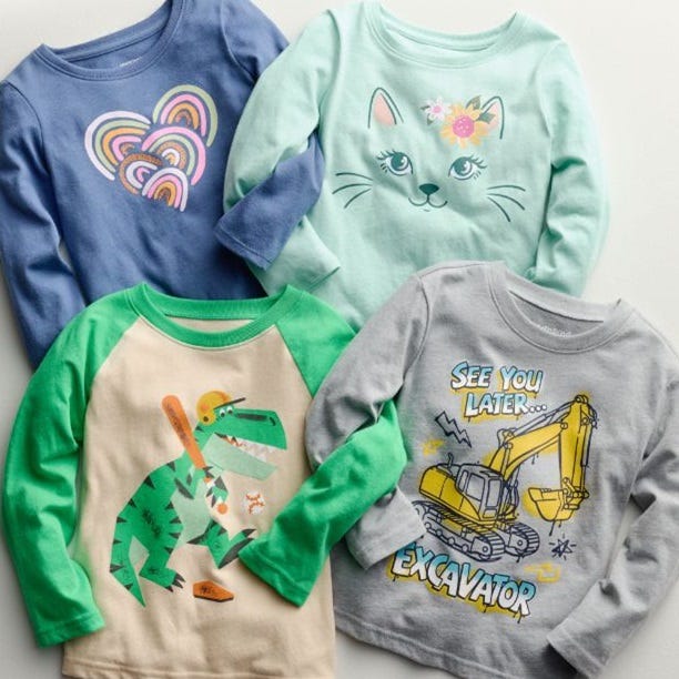Four children's long-sleeve shirts with colorful designs: hearts, cat face, dinosaur, and excavator.