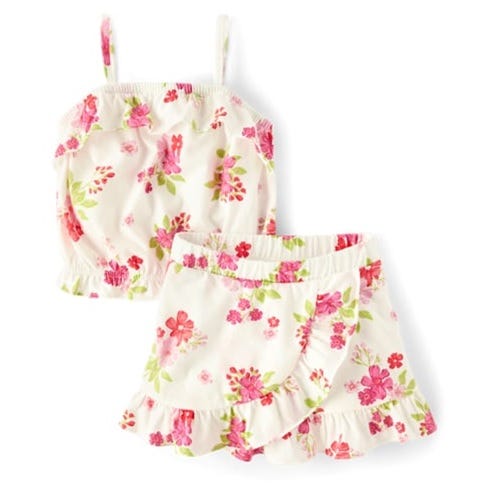 A two-piece outfit set featuring a white camisole and matching shorts, both adorned with a vibrant pink and green floral pattern. The garments have ruffled edges and spaghetti straps, creating a playful and summery look.