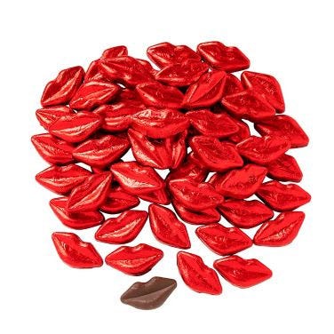 A collection of 57 foil-wrapped chocolates shaped like lips, primarily in shiny red foil with one in brown foil, arranged together.