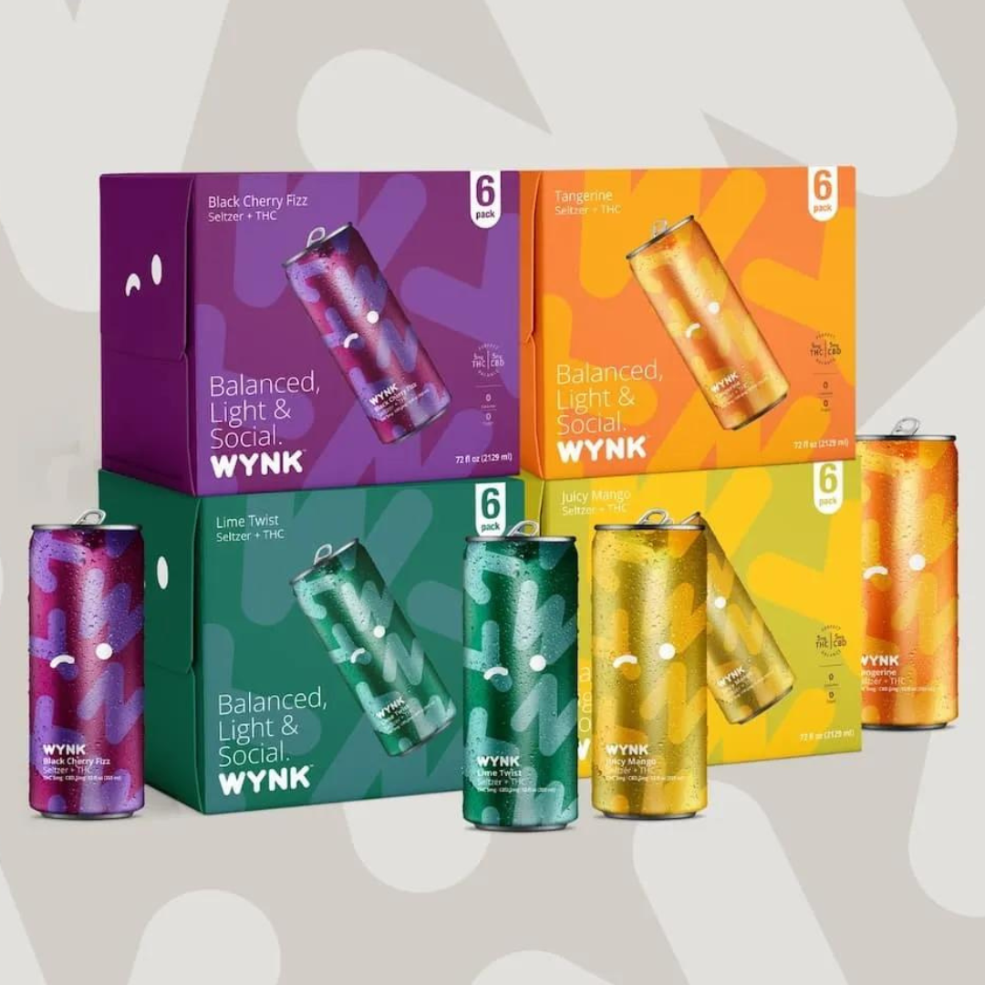 Four six-packs of WYNK seltzer cans in different flavors: Black Cherry Fizz, Tangerine, Lime Twist, and Juicy Mango.
