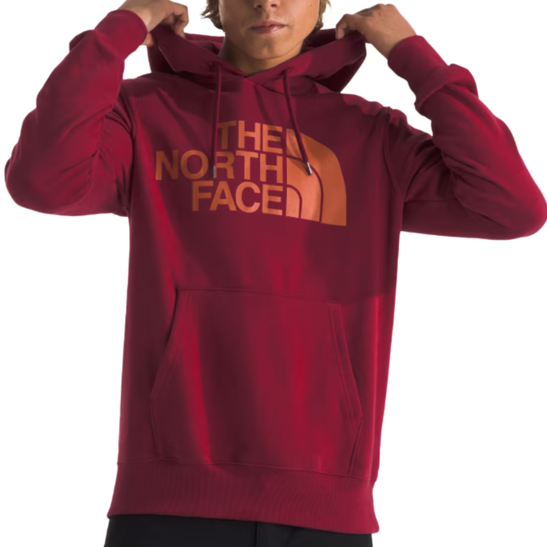 The North Face Men's Half Dome Hoodie is a red pullover with a front pouch pocket and the brand logo in orange on the chest, featuring adjustable drawstrings on the hood.