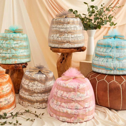 Stacks of diapers arranged in cake shapes with decorative ribbons on wooden stands.