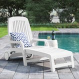 White poolside chaise lounge with adjustable backrest, geometric blue and white cushion, and a small round side table holding a bottle and a drink.