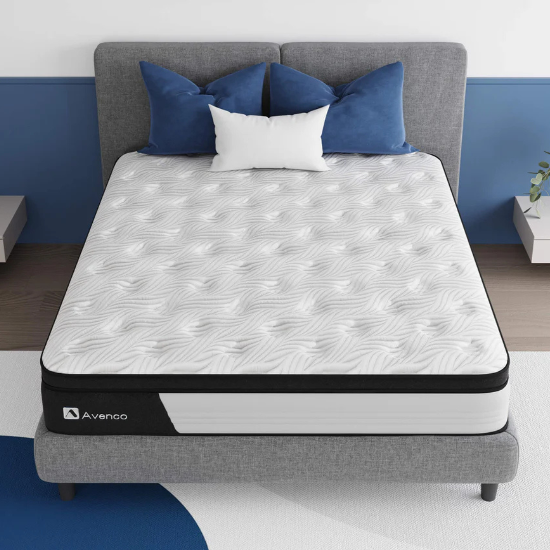 Avenco Queen Zone Hybrid Mattress features a wavy patterned surface with layers of foam and spring support, designed for comfort. It is displayed on a gray bed frame with blue and white pillows.