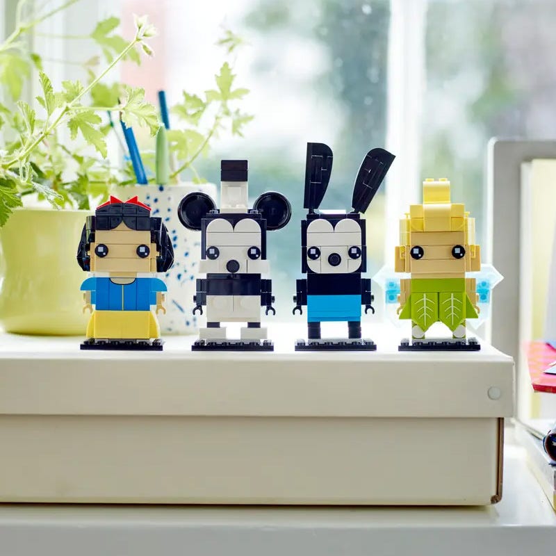 Four stylized plastic figures resembling simplified, blocky versions of human characters, displayed on a window ledge.