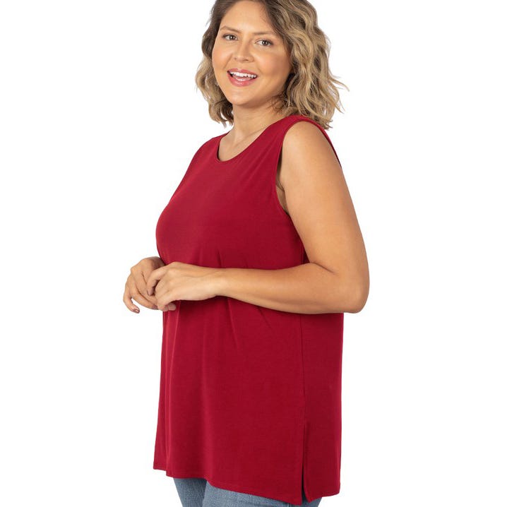 A woman wearing a sleeveless red top and blue jeans.