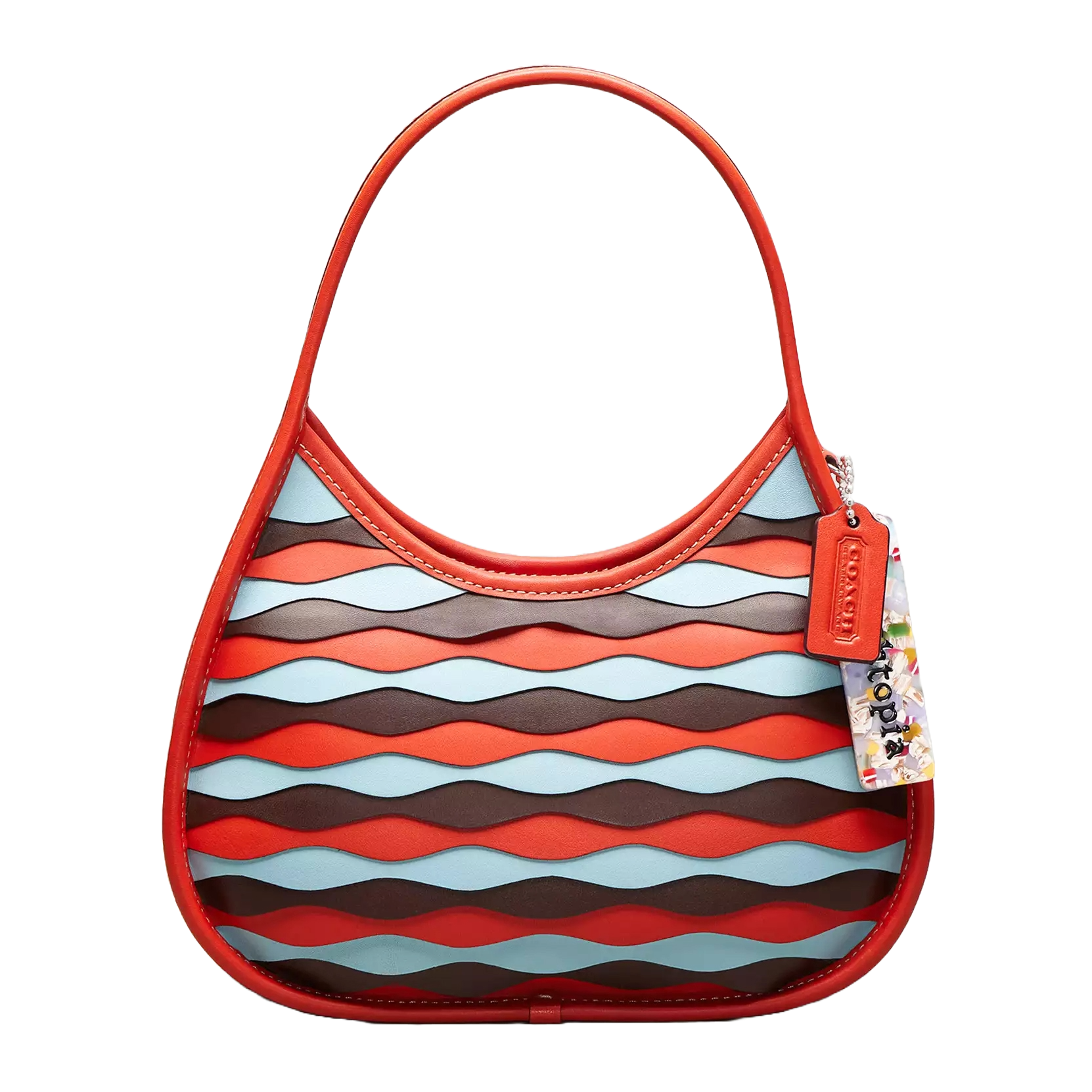 The Coach Ergo Bag features a red leather handle and trim with a colorful wavy applique design in red, blue, and brown tones. It includes a Coach tag and a decorative tag with an abstract pattern.