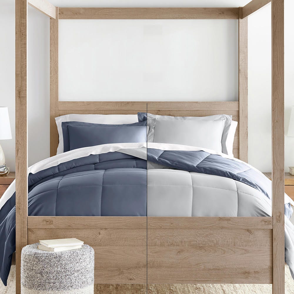 A wooden four-poster bed with gray and white bedding, including pillows, a striped duvet, and a comforter.