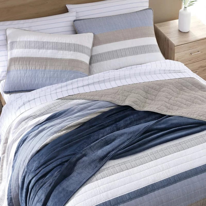 Striped bedding set with coordinating pillows on a bed.
