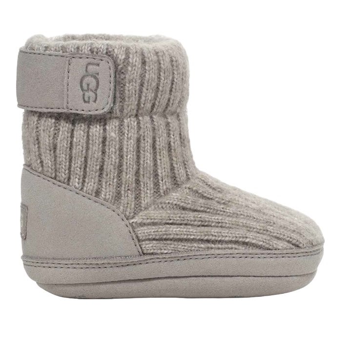 UGG Baby Skylar Boots are cozy, ankle-high booties featuring a ribbed knit upper with a soft, suede heel, and a Velcro strap for easy fastening. They have a plush, warm interior, ideal for keeping a baby's feet warm.