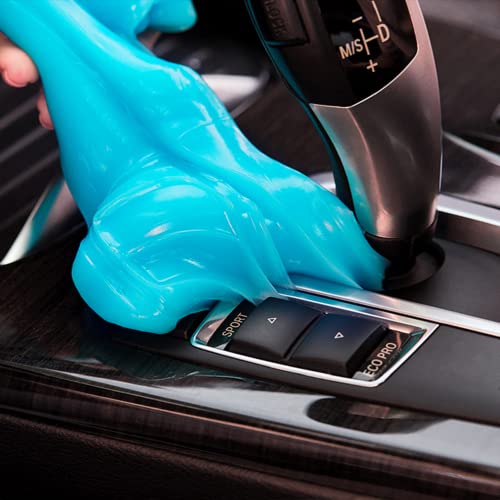 A blue, putty-like cleaning gel is being pressed over a car's interior console to clean and pick up dust from the surfaces and crevices.