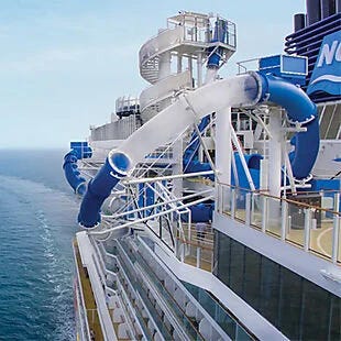 A blue water slide on a cruise ship deck beside the ocean.