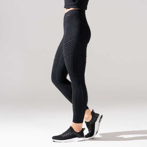 A person is wearing black leggings with a distinctive pattern of raised dots, designed for athletic use.