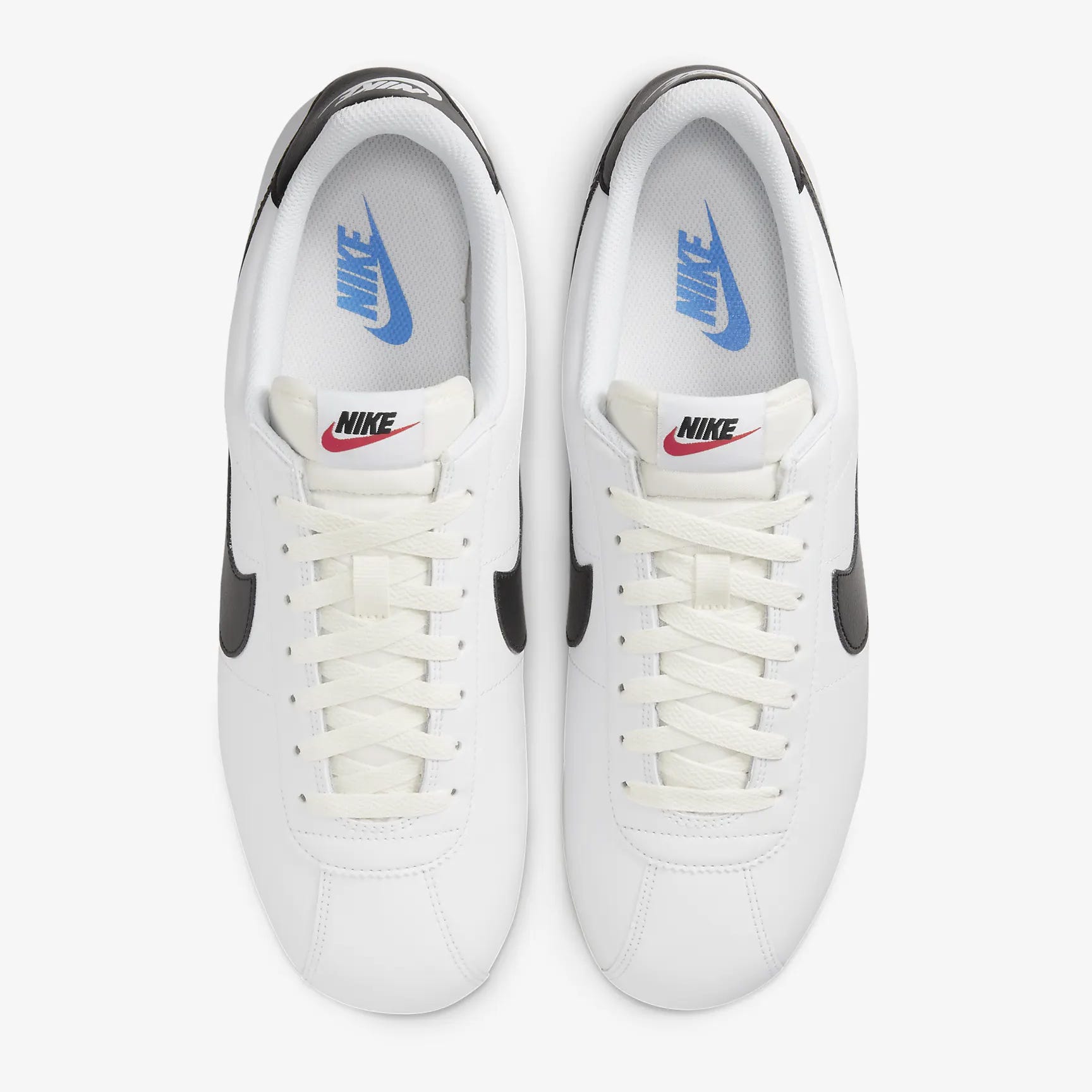 A pair of white sneakers with a distinctive swoosh logo on the sides, black accents, and laced fronts.