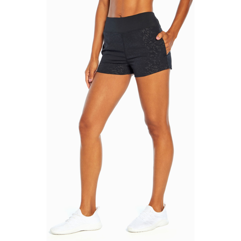 Black athletic shorts with a subtle floral pattern and side pockets, paired with white athletic shoes.