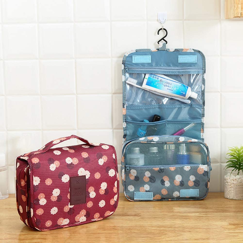 Two floral-patterned hanging cosmetic bags, one closed in maroon and the other open and hanging in blue. The open bag features multiple compartments with toiletries, displaying a hook and mesh pockets for easy organization.