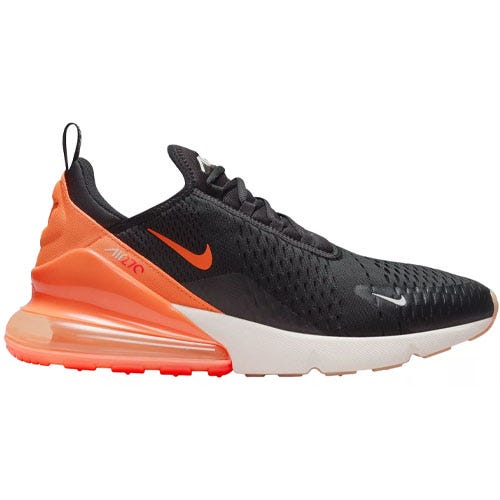 The Nike Air Max 270 features a predominantly black upper with orange accents and branding, a large air unit at the heel for cushioning, and a white midsole.