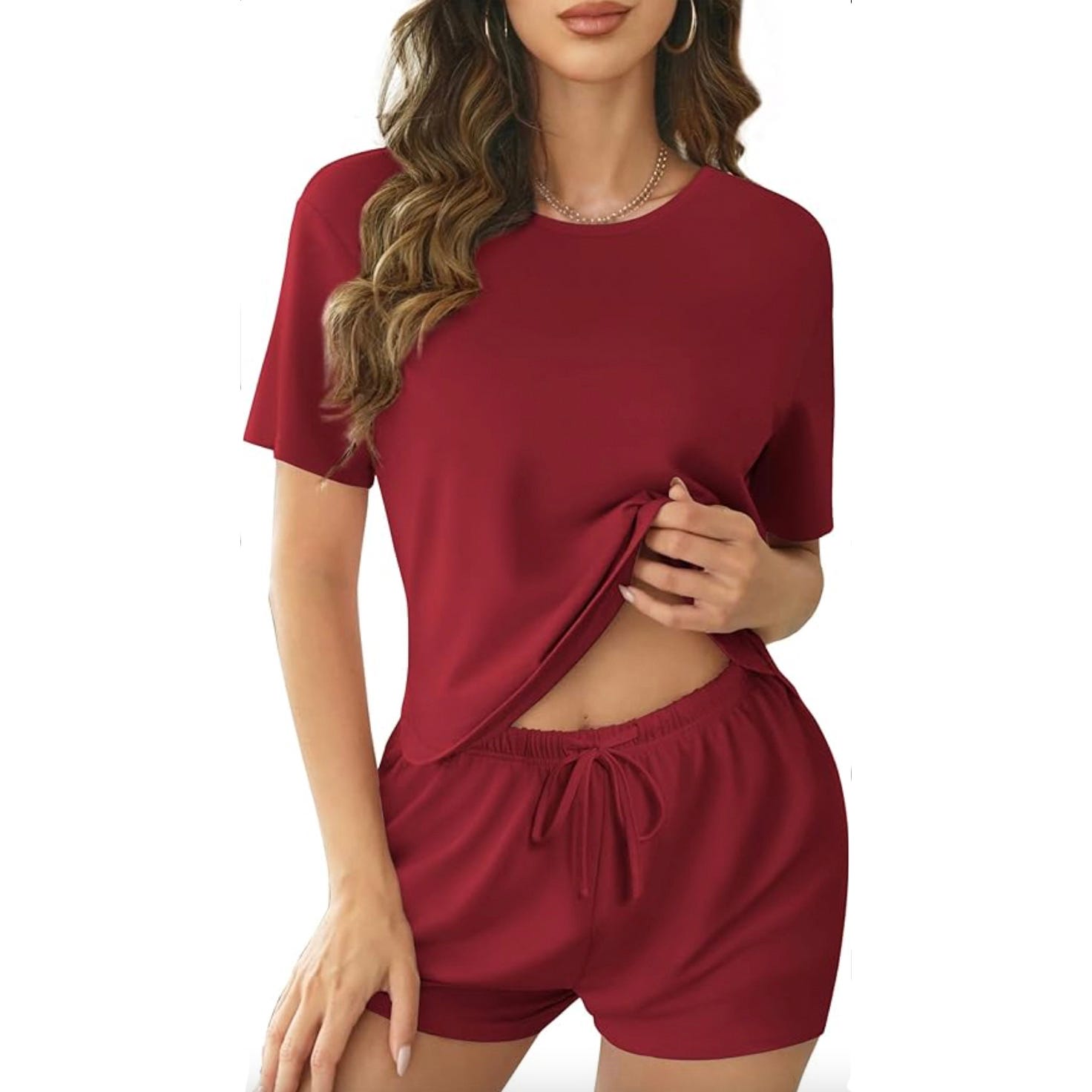 A woman is wearing a red short-sleeve top and matching shorts with a drawstring waist.