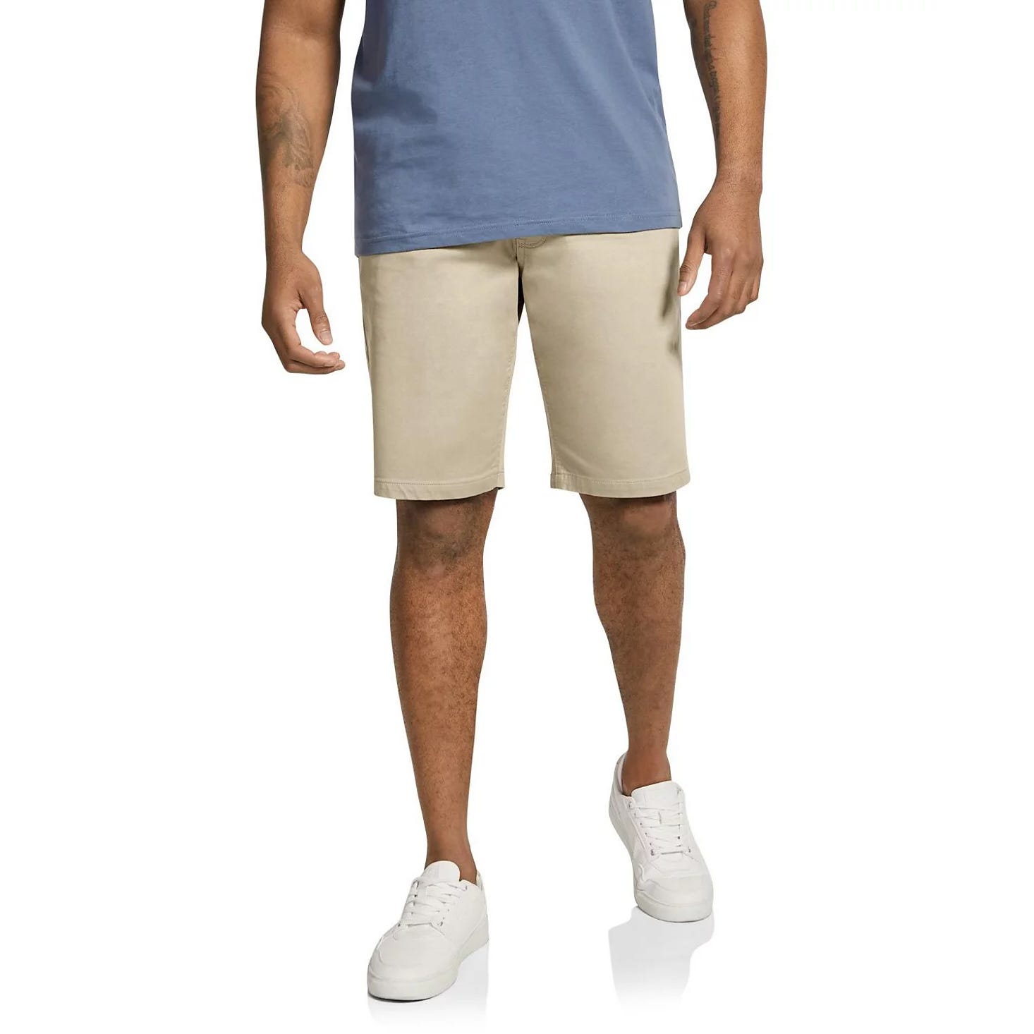 The Johnny Bigg Cameron Knit Shorts are beige, knee-length shorts made from a soft, stretchy knit material, suitable for casual wear. They are paired with a blue shirt and white sneakers.
