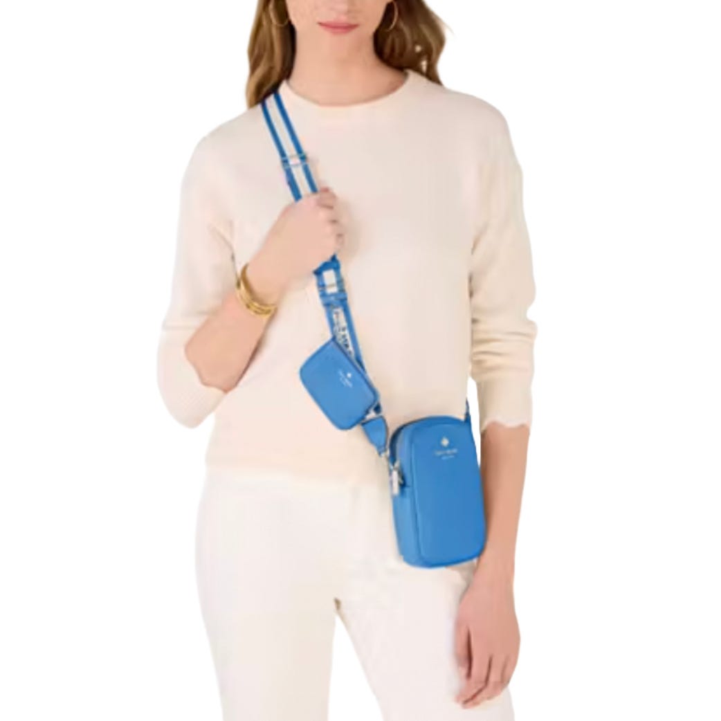 A woman is wearing a white sweater and pants, carrying a blue crossbody bag with an additional small pouch attached to the strap.
