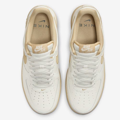 A pair of beige Nike Air sneakers viewed from above.