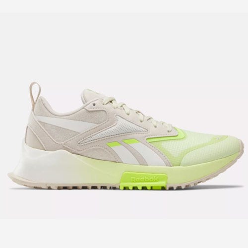 A pair of beige and neon green Reebok sneakers with a white sole.