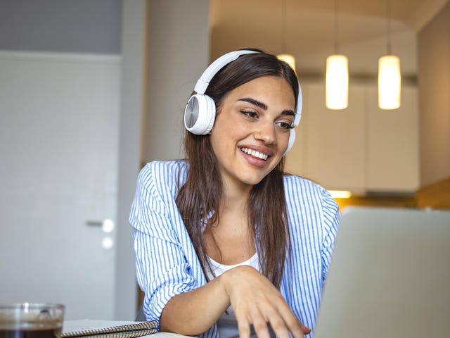 Woman with a headphone learning a language with Berlitz Nicaragua on her laptop