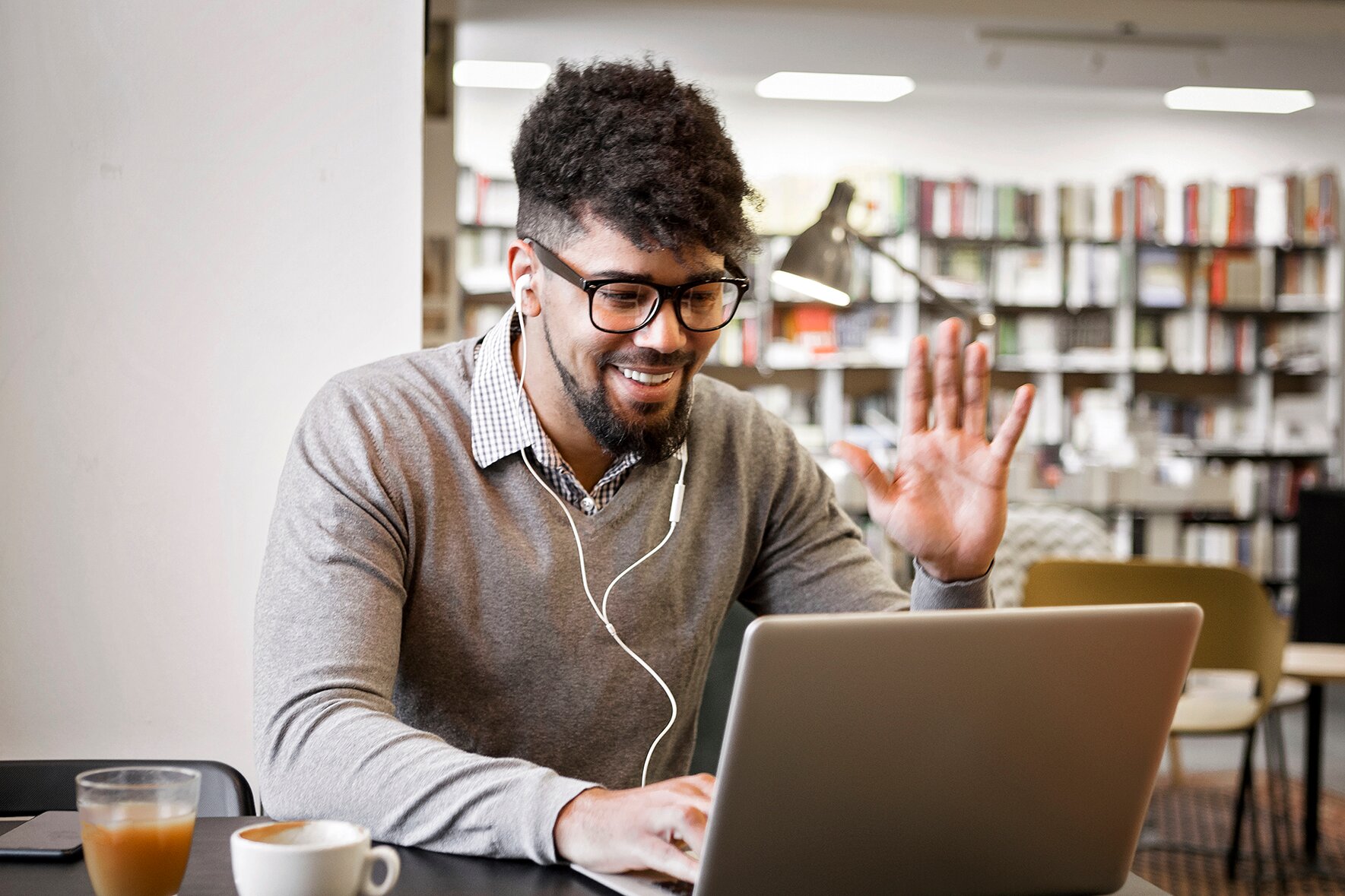 Man in headphones waving at his instructor at the beginning of his online language class with Berlitz Nicaragua