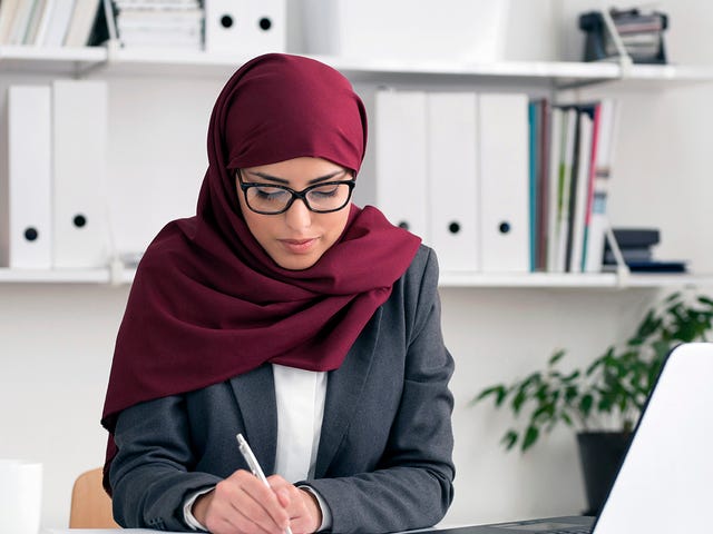 Woman at her desk learning a language online with Berlitz Nicaragua's classes and making notes