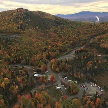 An aerial view of the Team O’Neil property in New Hampshire’s White Mountains. It’s a 583-acre facility with 600 feet of elevation change over 6 miles of roads. There are more trees than roads, and the deciduous trees are in muted colors of greens, reds and yellows.