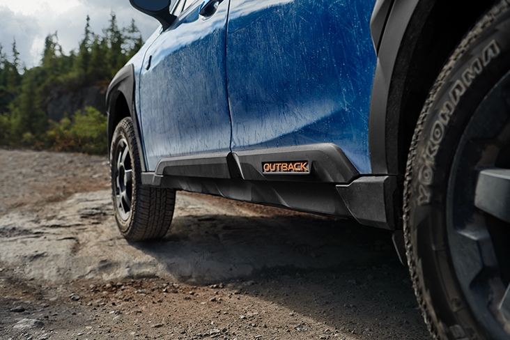 Closeup shot of the 2022 Outback Wilderness vehicle’s front tires driving over rock and dirt trails.