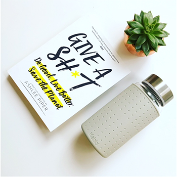 Author Ashlee Piper's book, Give a Sh*t: Do Good. Live Better. Save the Planet. is on a white background with a small succulent plant and a Kablo bottle.