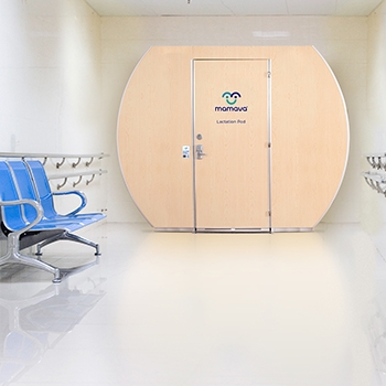 A Mamava pod in a well-lit room with a bench.