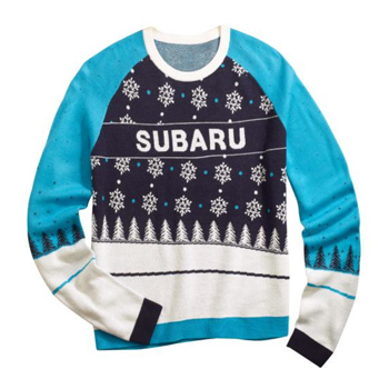 A navy crew neck sweater with bright blue sleeves has a woven snowflake and tree patten. The words “SUBARU” are across the chest.